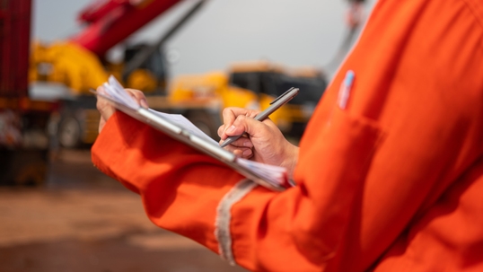 An engineer or foreman is checking on safety checklist form of lifting crane at the drilling rig work site